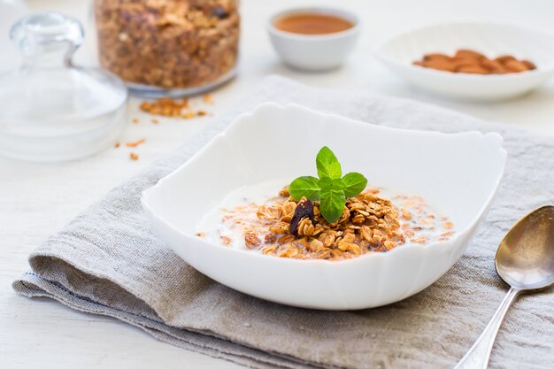 Granola with milk, honey and nuts on a white table