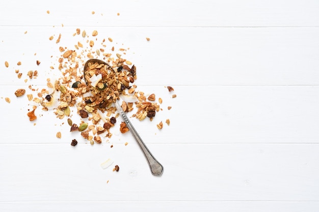 Muesli con noci e frutta secca su fondo di legno bianco vista dall'alto