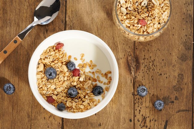 Granola with yogurt and berries in a white bowl on a wooden table