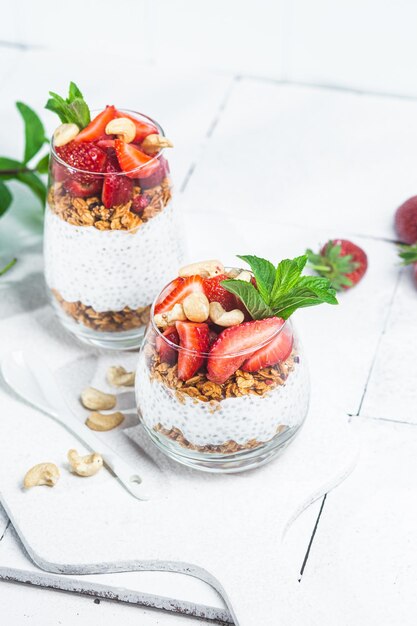 Granola with yogurt chia and strawberries in a glass on a white background