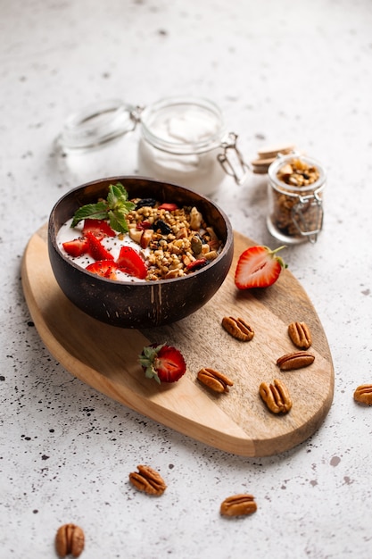 Yogurt muesli con fragole e semi di chia sulla tavola di legno