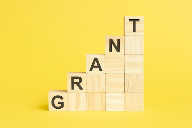 Grant text on wooden cubes yellow background