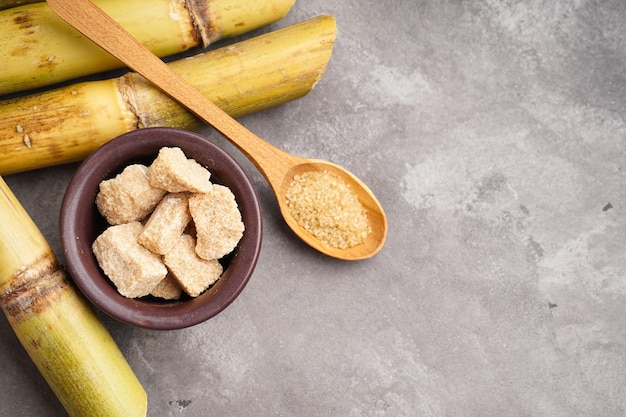 Granulated brown sugar and sugar cane on a gray background space for text Top view