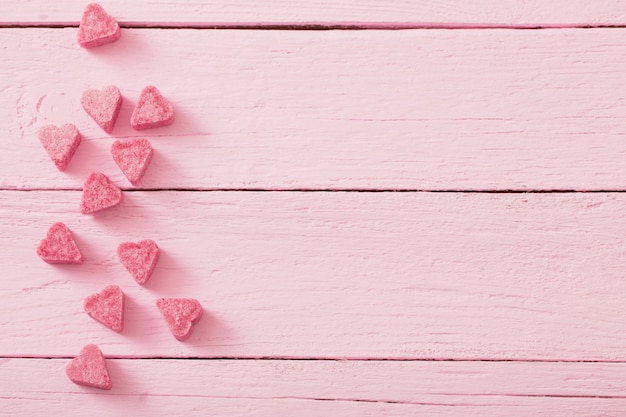 Granulated pink sugar  in the shape of heart on a wooden space