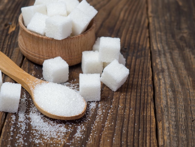 Granulated sugar on a wooden spoon closeup on an old wooden table