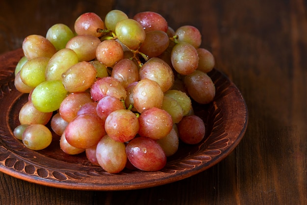 Grape on brown plate on dark wooden background