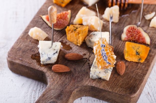 Grape, cheese, figs and honey with a glasses of red and white wine on a wooden Board
