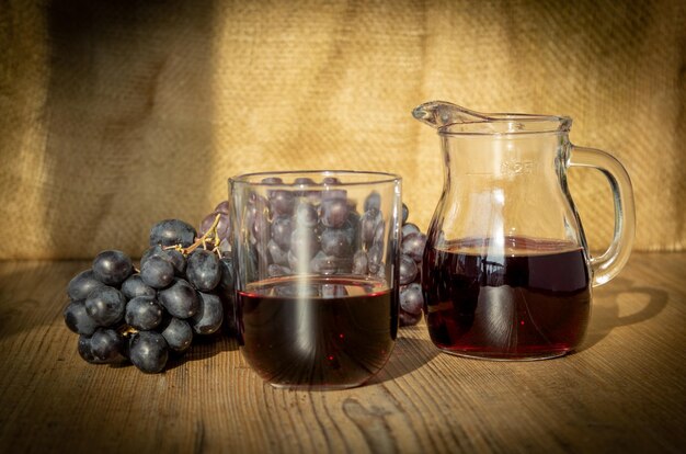 Foto glassa d'uva e caraffa di vino rosso a tavola