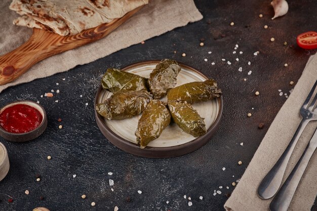 Foto foglie di vite con carne, cucina georgiana, sfondo scuro con texture