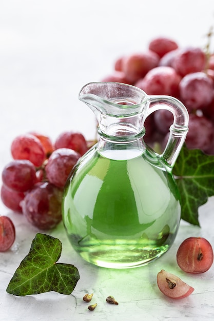 Grape seed oil in a glass bottle with a bunch of grapes.