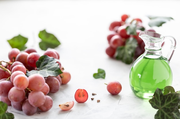 Grape seed oil in a glass bottle with a bunch of grapes.