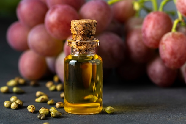 Grape seed oil in a glass jar and fresh grapes