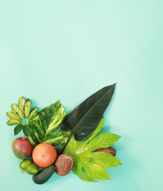 Grapefruit coconuts mangoes avocados and limes on tropical leaves Photo with exotic fruits