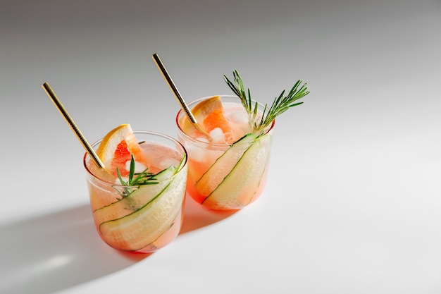 Grapefruit en komkommer Gin Cocktail op elegante glazen op witte achtergrond met schaduwen