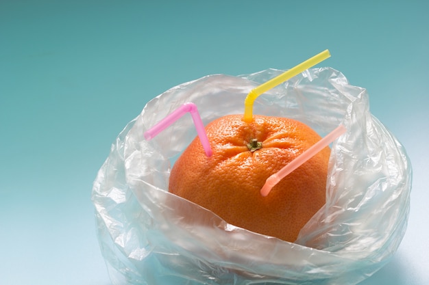 Grapefruit met plastic rietjes in een plastic zak