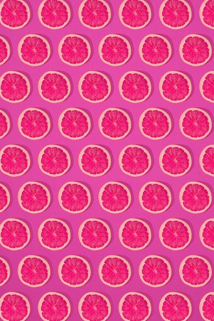 ピンクの背景にグレープフルーツのパターン。最小限のフラットレイコンセプト。印刷