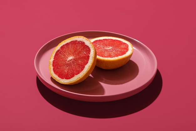 Grapefruit on pink plate isolated on a magenta background