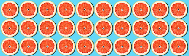 Grapefruit rings on a blue background Bright juicy background Concept