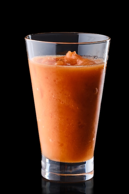 Grapefruit smoothie in tall glass isolated on black surface