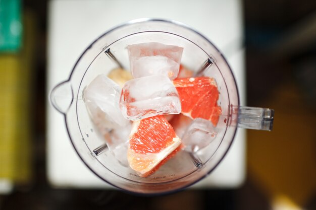 Grapefruit smoothie with ice in blender, diet and healthy eating concept