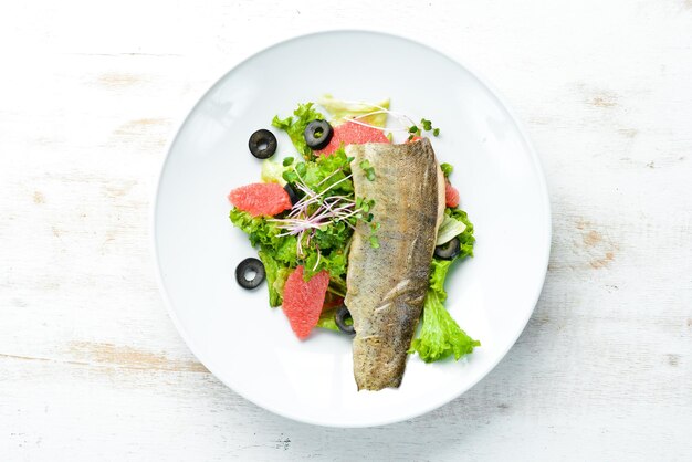 Grapefruit vegetable salad and trout fillet on a plate Top view free space for your text Rustic style