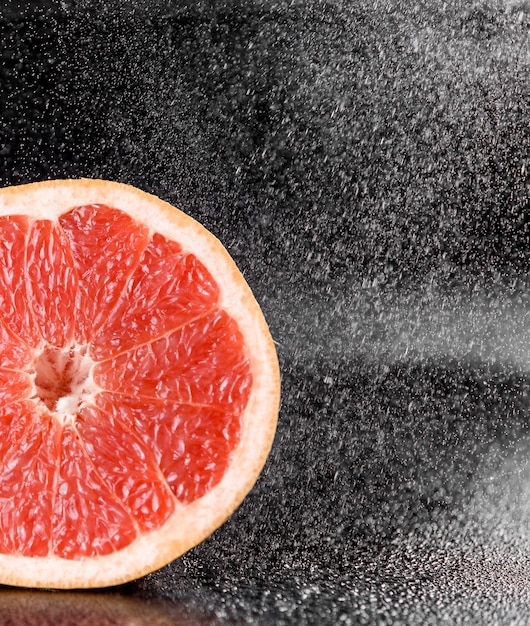 Grapefruit with water drops on black surface