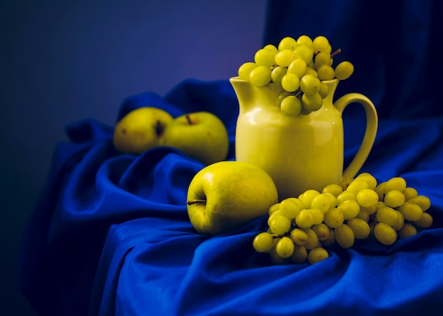 Grapes and apples in a jug on a table