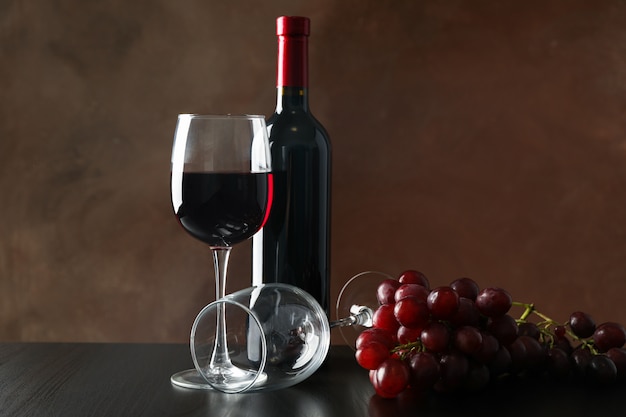 Grapes, bottle and glass with wine against brown