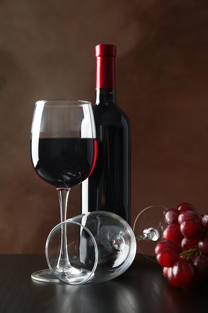 Grapes, bottle and glass with wine against brown