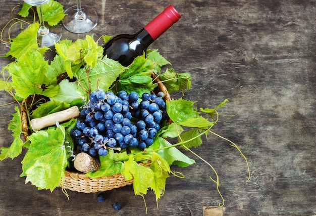 Grapes,a bottle of wine, corks and corkscrew on a wooden old table, rustic style