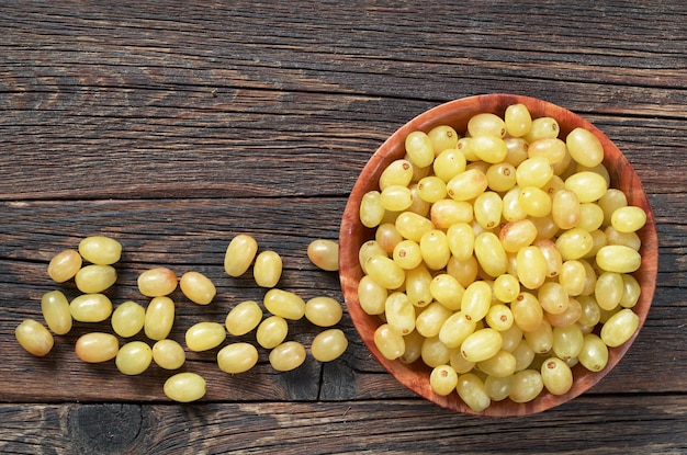 Grapes in bowl and near on dark wooden table top view Space for text