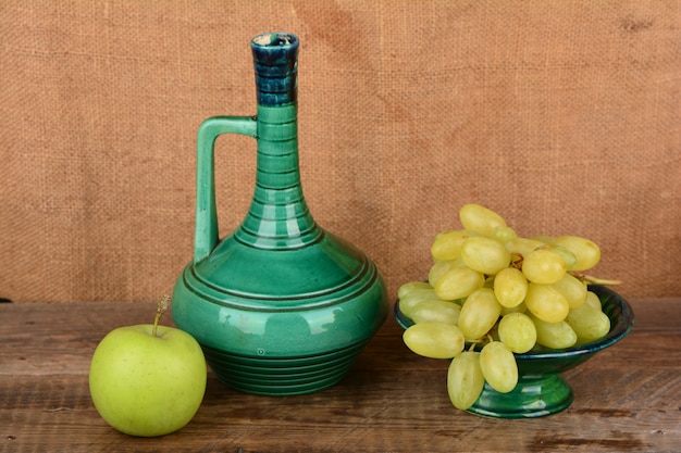 Grapes in a ceramic vase a jug of wine