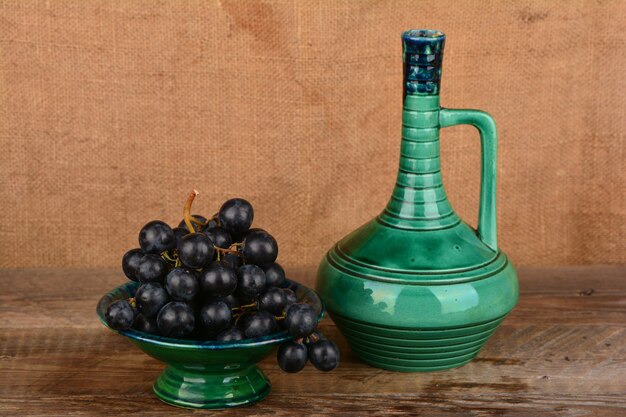 Grapes in a ceramic vase a jug of wine