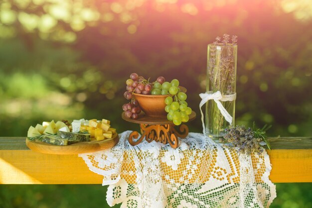 Grapes, cheese, lavender flowers, vase on white tablecloth