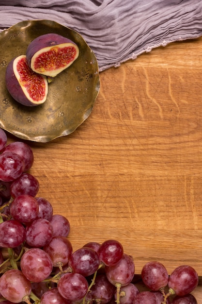 Grapes, copper plate and figs on a wooden board