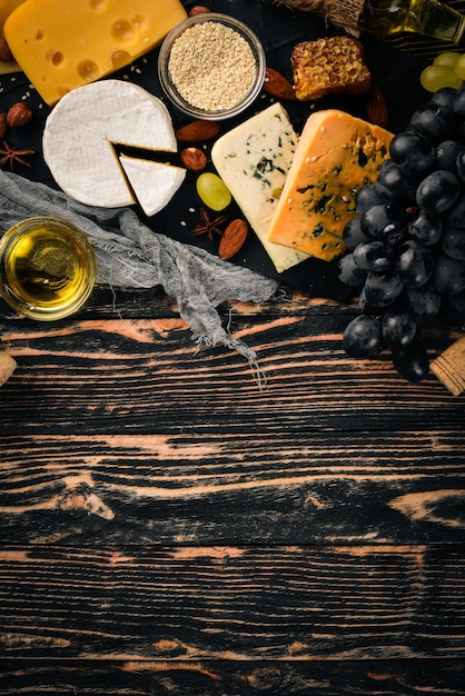 Grapes red wine cheeses honey and nuts on a wooden background Top view