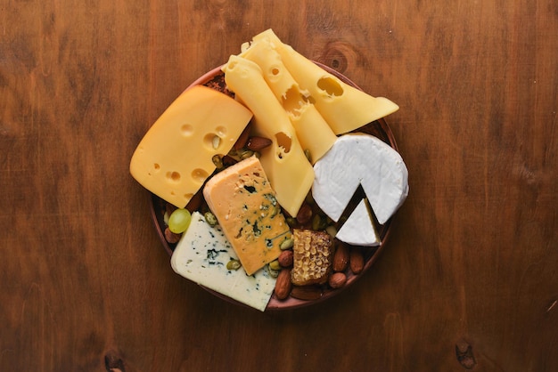 Grapes, red wine, cheeses, honey and nuts on a wooden background. Top view.