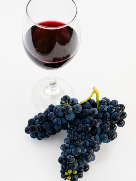 Grapes and red wine in glass on white backgound.