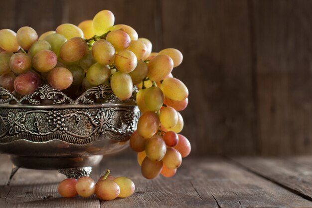 Grapes in silver bowl on a wooden table close up