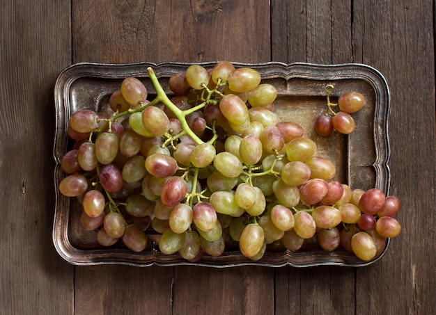 Grapes on silver tray top view on wooden table