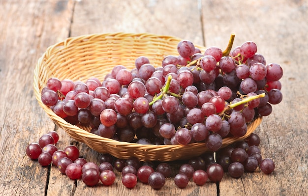 Grapes in a wicker basket on wooden table