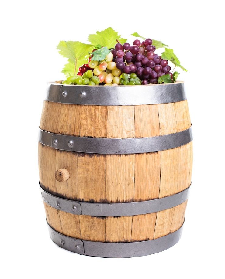 Photo grapes on wooden barrel with wine isolated on white