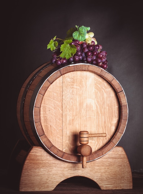 Grapes on wooden barrel with wine on a white
