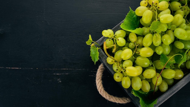 Grapes in a wooden box Leaves of grapes Top view On a black background Free space for text