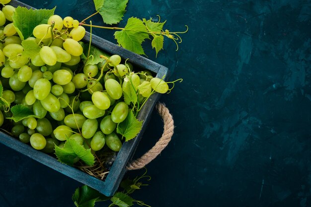 Grapes in a wooden box Leaves of grapes Top view On a black background Free space for text