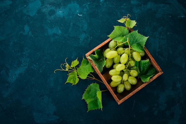 Grapes in a wooden box Leaves of grapes Top view On a black background Free space for text