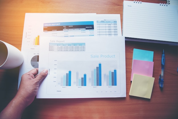 graph chart business document and coffee cup on Wood Table.
