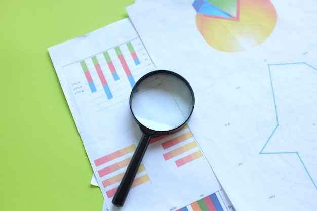 graph document and magnifying glass on green background