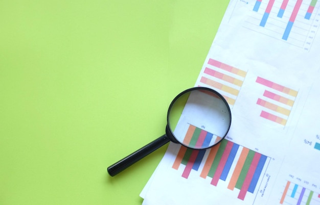 graph document and magnifying glass on green background
