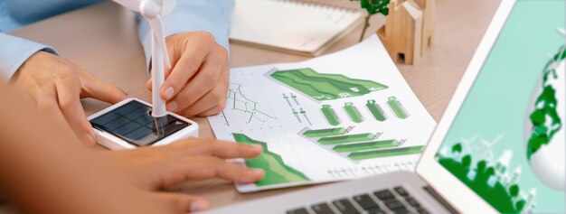 Photo the graph shows the result of using renewable energy increase profit was placed on the table with windmill model represented using renewable energy environmental friendly concept delineation